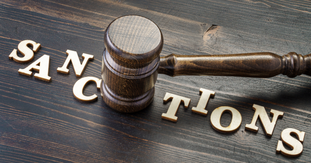 gavel pounding down on the word "Sanctions" which is laying on a wooden surface